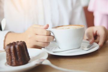 woman hands with cappuccino coffee on a wood table