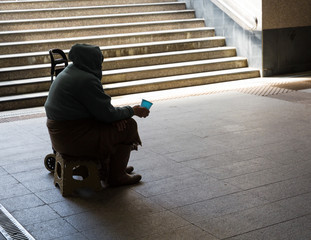 Silhouette of elderly woman asking for alms in the underpass. Concept of social degradation