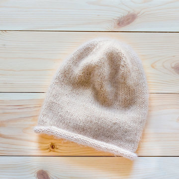 Hat knitted beige wool on wooden background