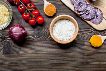 paella ingredients with rice, salt, spices and tomatoes on wooden table background top view mockup