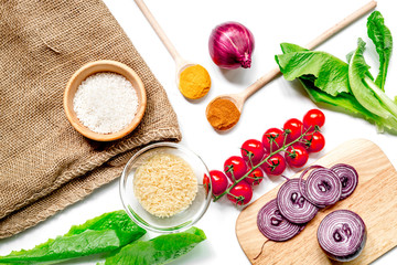 homemade paella ingredients composition with rice, tomato, onion on white table background top view