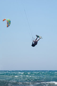 People practicing Kitesurfing. Beach on the peninsula Prasonisi, Rhodes. Colorful kites on the sea shore. Blue sea and windsurfing.