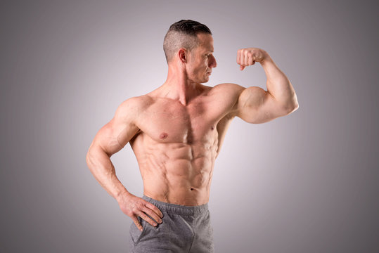 fit muscular man posing isolated on a grey background