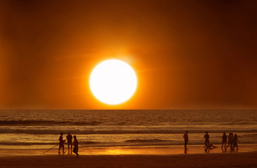 People on the beach in the water at sunset, ocean, vacation.