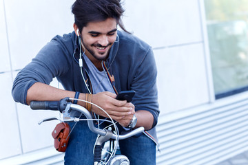 Fototapeta na wymiar Young handsome guy on a bicycle looking at mobile phone.