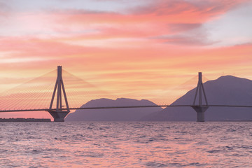 Naklejka premium Bridge Rio - Antirrio in Greece over Gulf of Patras, Amazing sunset scenery, purple colored epic sunset sky. Patras bridge is famous landmark and the longest bridge with cable-stayed construction. 
