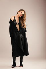 Fototapeta premium Beautiful stylish woman in dark coat on color background