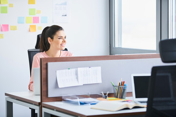 Confident young employee working at her desk