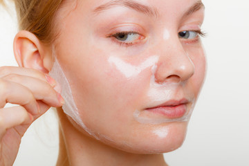 Woman removing facial peel off mask.