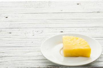 slice of pineapple in white plate on wooden table