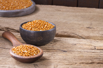 Red millet grains in bowl on wood