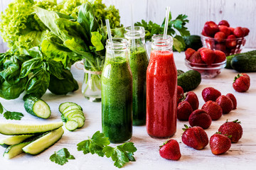 Fresh green smoothies and strawberry smoothie with ingredients on a light wooden background. Healthy detox drinks.