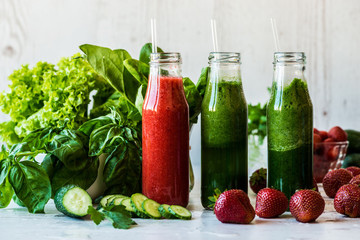 Fresh green smoothies and strawberry smoothie with ingredients on a light wooden background. Healthy detox drinks.