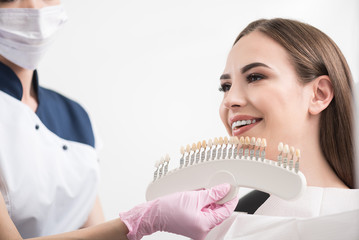 Odontologist selecting dental crown to outgoing woman