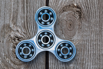 design element. 3D illustration.rendering. fashionable modern metal toy fidget spinner on wood...