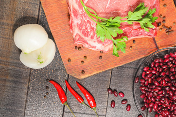 A raw piece of beef with pepper, carrots, beans and garlic