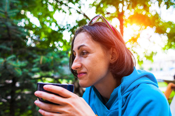 A woman is drinking coffee in the park.