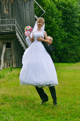 Fototapeta premium happy bride and groom jumping near the old mill on village