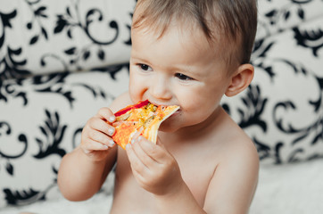 The boy eats a piece of delicious pizza