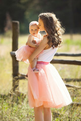 Young pretty mother with her little baby outdoors. Beautiful woman with her daughter on the nature. infant child with her parent