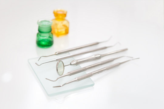 Dental mirror and other professional tools set in dentist clinic on white desktop, macro shot of shiny basic metal medical equipment