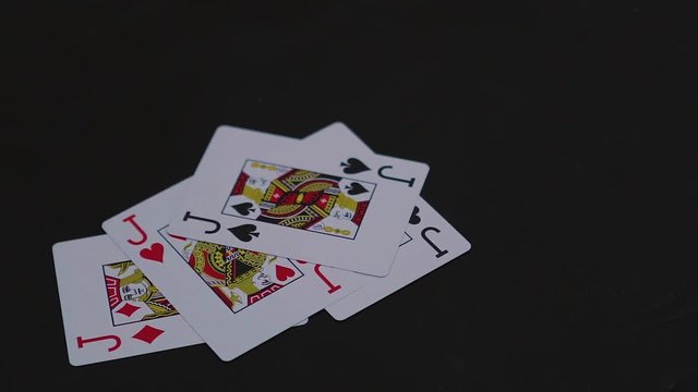 Four jack poker cards falling on the black table