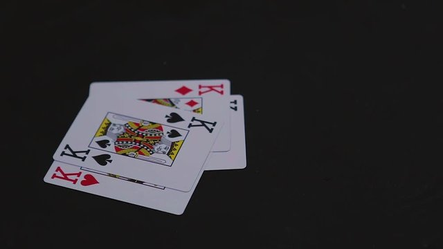 Four king poker cards falling on the black table