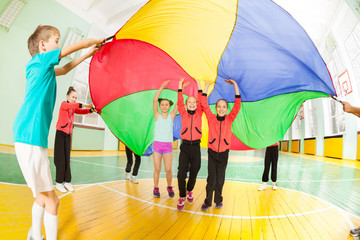 Children playing parachute games in sports hall