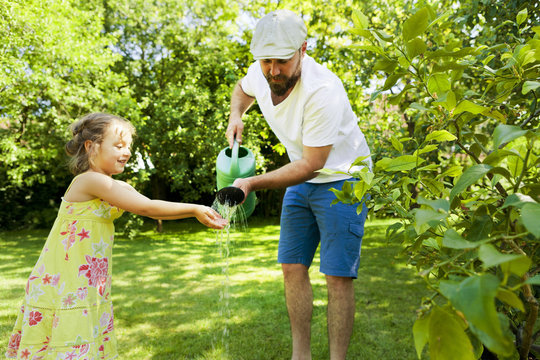 Father and daughter watering plants together, Munich, Bavaria, Germany