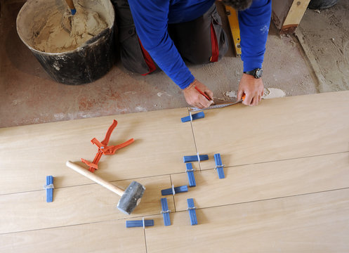 Bricklayer who is writing down the measure to place the next row of porcelain stoneware tiles on the living room floor