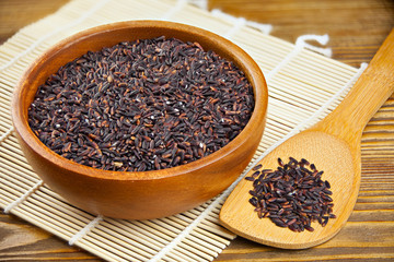 Raw black rice in bowl on  wooden background