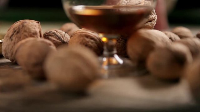 A beautiful comic strip from a glass of cognac and walnuts against the background of a dark background and a burning candle.Perfectly suitable for the final frame for advertising cognac, rum, whiskey.