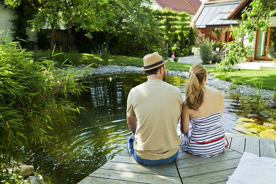 Heterosexual couple takes a break by the pond, rear view, Munich, Bavaria, Germany