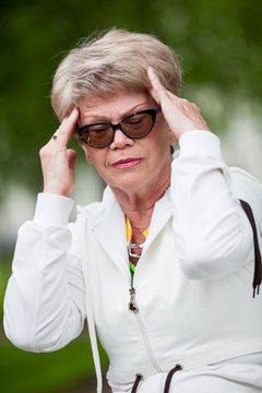 Portrait of senior European woman with temporal headache, outdoor
