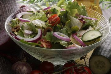bowl of salad with vegetables and greens on wooden table