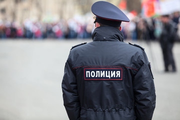Russian policeman officer standing back to camera with inscription Police on the uniform jacket,...