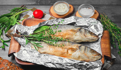 Grilled whole trout on an aluminum foil on a wooden log