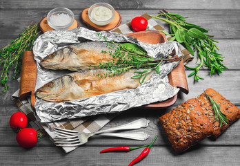 Grilled whole trout on an aluminum foil on a wooden log
