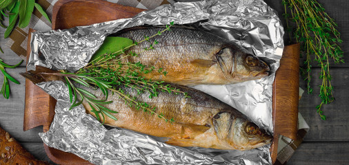 Grilled whole trout on an aluminum foil on a wooden log