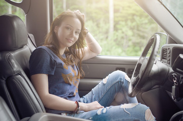 Pretty girl traveler sitting in the car and resting from a long journey in Sunny weather