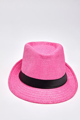 Pink woven hat, white background. Summer headgear accessory for beach.