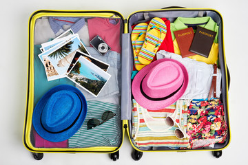 Yellow suitcase packed with clothes. Man and woman summer rest accessories.