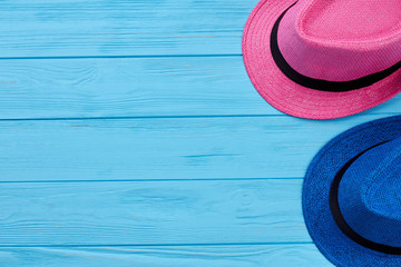 Two colorful summer hats. Woven headgear on blue wooden vintage background.