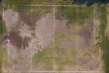 Vista aerea perpendicolare di un campo di rugby in erba trasandato e poco curato