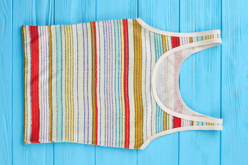 Female summer shirt in colorful stripes. Horizontally lying striped cotton shirt, wooden background.
