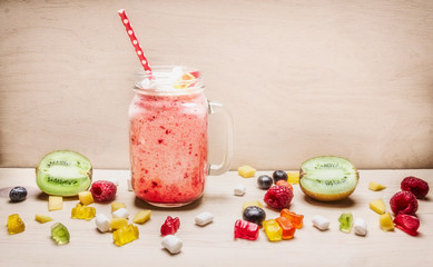 fresh fruit smoothies with berries, marshmallows, kiwi and jelly in bank with a pen on a white background wooden  close up