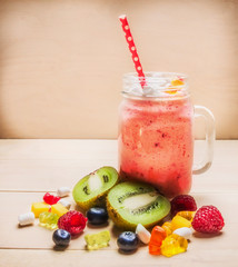 Fruit smoothies with berries on white wooden table, near a variety of ingredients laid out, close up
