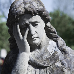 Vintage image of a sad angel on a cemetery against the background of leaves