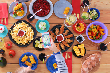 Top view of group of people having dinner together while sitting at wooden table. Food on the table. People eat fast food. Photograph food