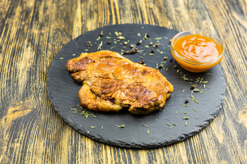 Grilled pork steak on black stone background.